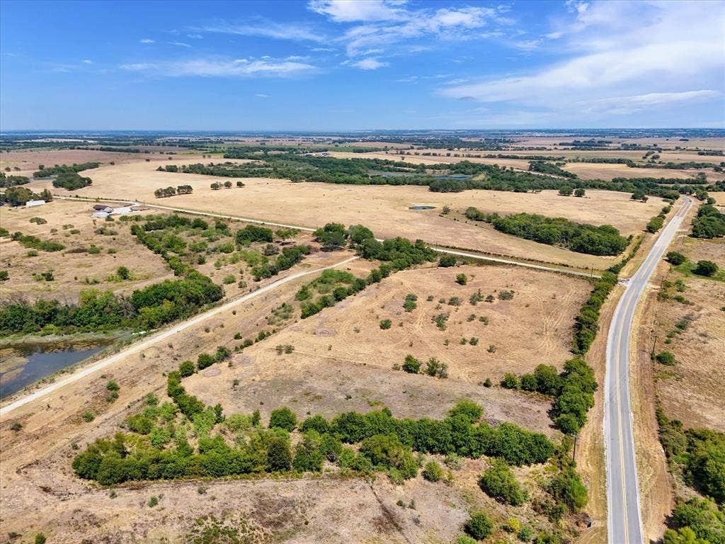TBD Horne Hill Road, Moody, TX 76557 Expansive open land featuring a paved road, scattered mature trees, and a visible pond