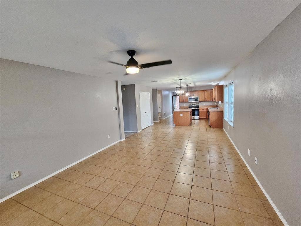 1229 Pine Forest Drive, Princeton, TX 75407 Tiled flooring throughout, ceiling fan with integrated lighting, kitchen featuring wood-finish cabinetry, stainless steel range, and a kitchen island