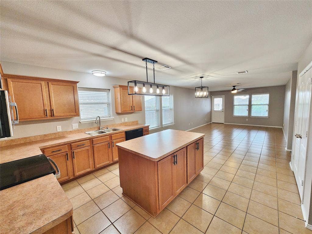 1229 Pine Forest Drive, Princeton, TX 75407 Open-concept kitchen with wood-finish cabinetry, a large center island, and tile flooring