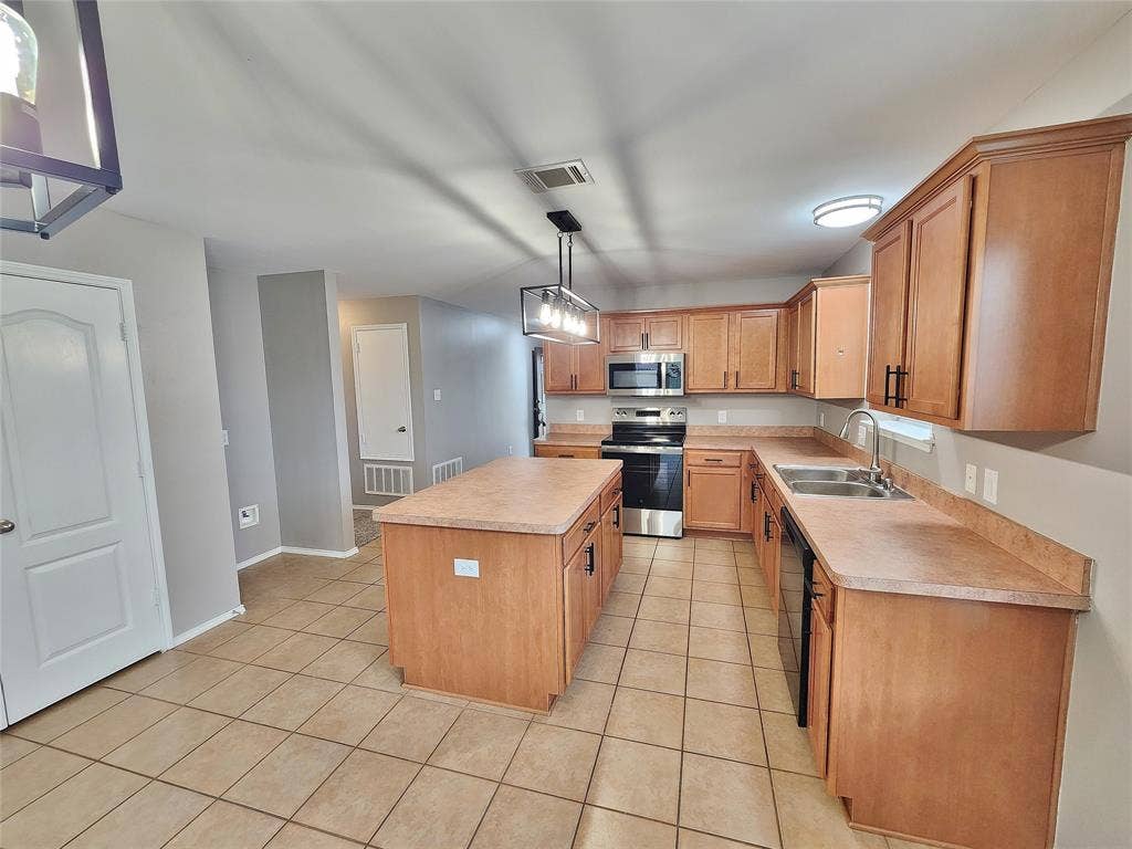 1229 Pine Forest Drive, Princeton, TX 75407 Kitchen featuring an island, integrated stainless steel appliances, wood-finish cabinetry, a double basin sink, and tile flooring