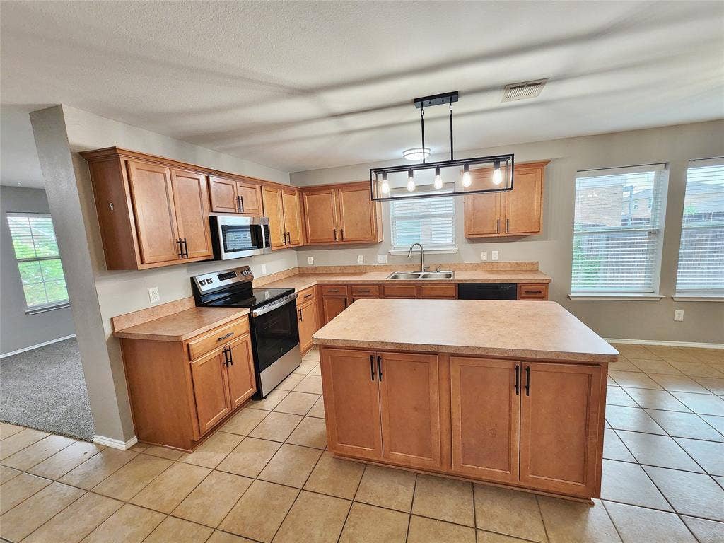 1229 Pine Forest Drive, Princeton, TX 75407 Kitchen featuring tile flooring, wood-finish cabinetry, a central island, stainless steel appliances, and multiple windows