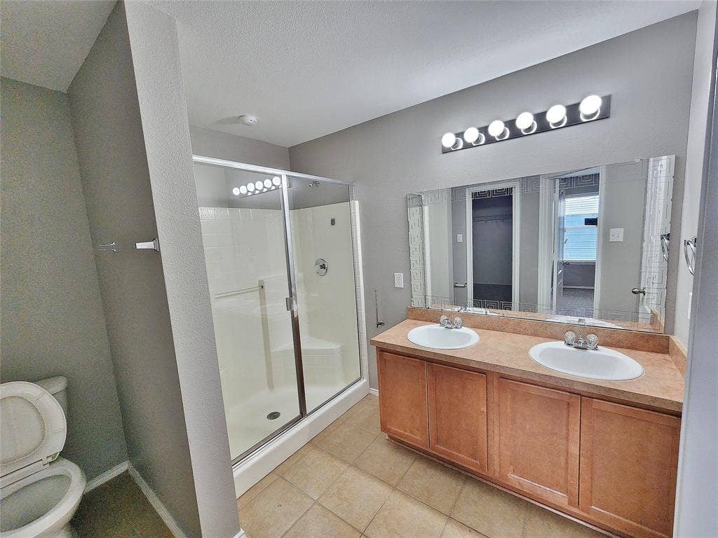 1229 Pine Forest Drive, Princeton, TX 75407 Dual vanity with integrated sinks, wood-finish cabinetry, a large mirror, and a multi-bulb light fixture