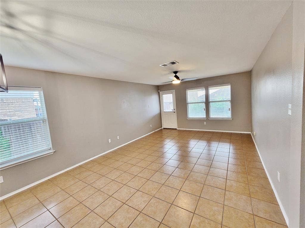 1229 Pine Forest Drive, Princeton, TX 75407 Spacious room featuring tile flooring, neutral wall tones, multiple windows with blinds, and a ceiling fan with integrated lighting