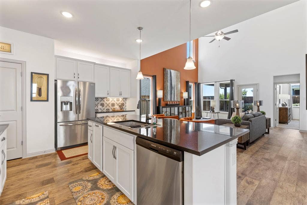 1456 Kit King Drive, Little Elm, TX 75036 Open-concept kitchen featuring an island with a sink, stainless steel appliances, and wood-finish flooring