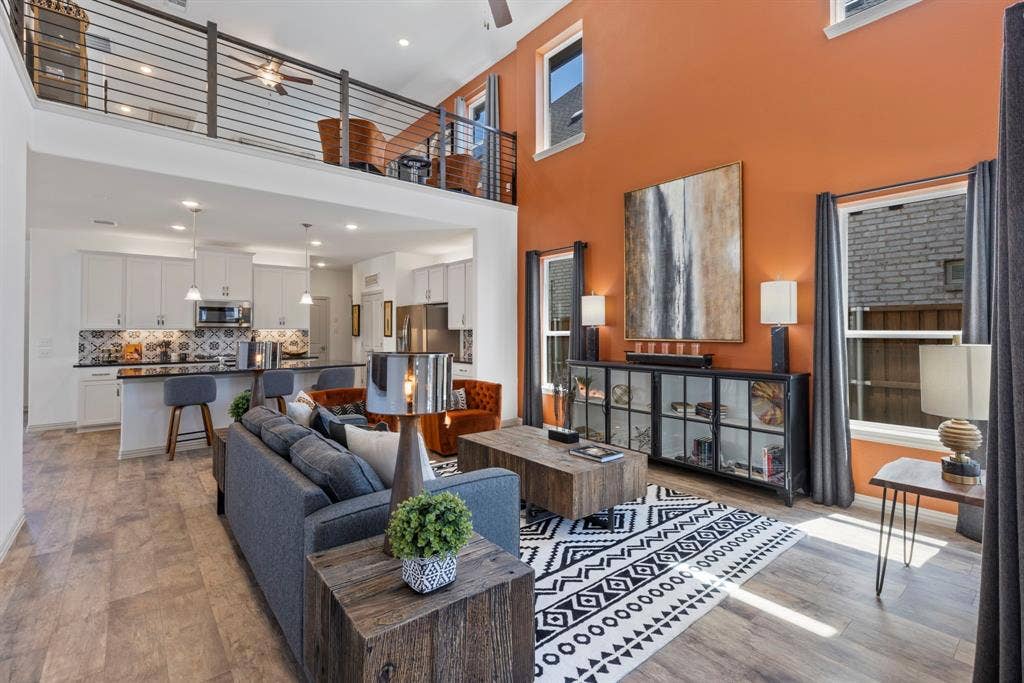 1456 Kit King Drive, Little Elm, TX 75036 Soaring ceilings, wood-finish flooring, two-story windows, open-concept kitchen with a breakfast bar, and an upper-level loft with metal railings