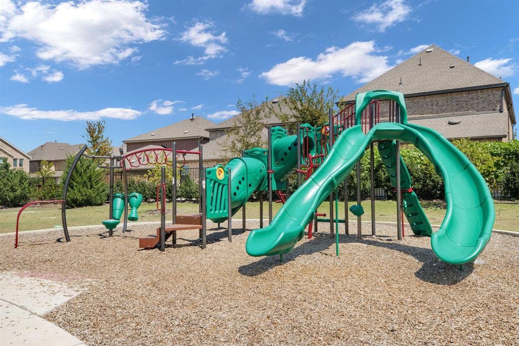 1456 Kit King Drive, Little Elm, TX 75036 Community playground featuring a multi-level structure with slides, climbing elements, and a wood chip surface