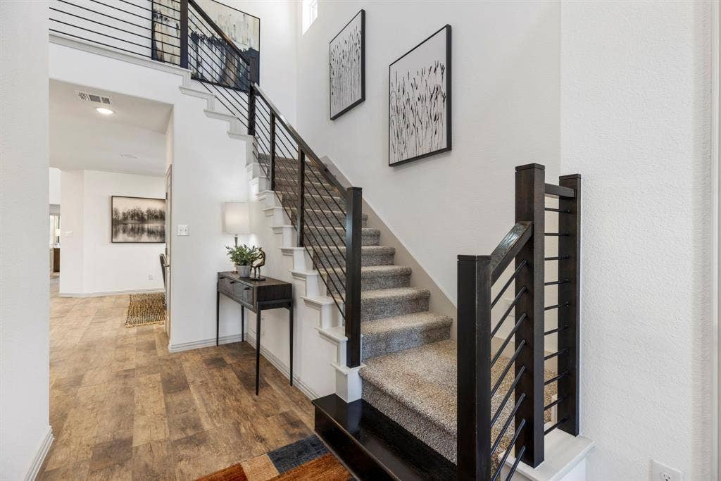 1456 Kit King Drive, Little Elm, TX 75036 Staircase with horizontal metal balusters, carpeted treads, and wood-finish newel posts