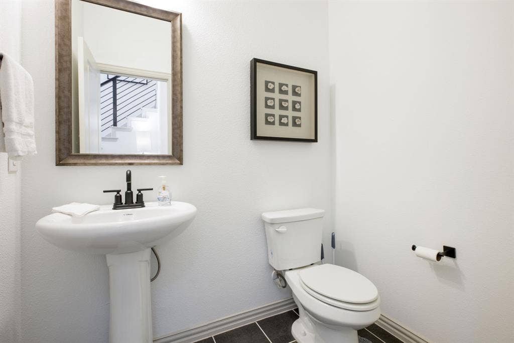 1456 Kit King Drive, Little Elm, TX 75036 Pedestal sink with black-finish faucet, framed mirror, and dark-finish flooring