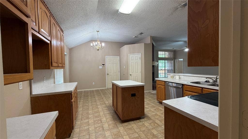 2718 High Pointe Boulevard, McKinney, TX 75071 Kitchen featuring wood cabinetry, white countertops, stainless steel appliances, a center island, and vaulted ceilings