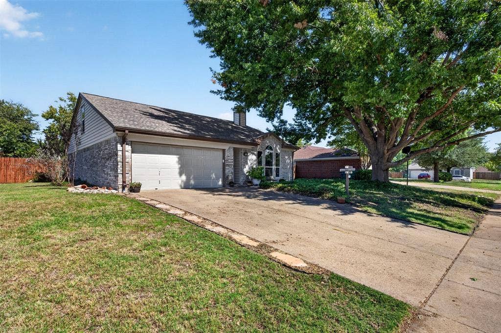 203 Briarglen Drive, Cedar Hill, TX 75104 Exterior featuring a two-car garage, brick and siding facade, arched window with divided lites, mature tree, and concrete driveway