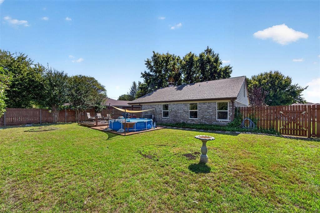 203 Briarglen Drive, Cedar Hill, TX 75104 Expansive backyard featuring a large grass area, wood privacy fencing, and a raised wood deck with an above-ground pool