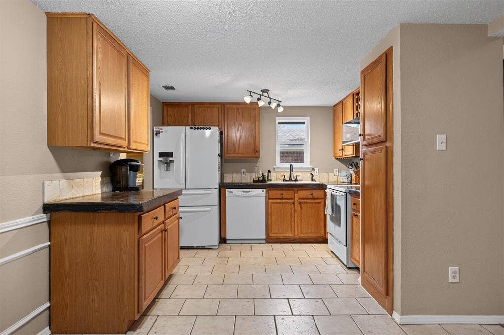 203 Briarglen Drive, Cedar Hill, TX 75104 Kitchen featuring wood cabinetry, white appliances, tile flooring, and dark countertops