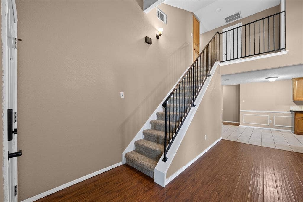 203 Briarglen Drive, Cedar Hill, TX 75104 Two-story entry with wood-finish flooring, carpeted staircase, wrought iron railing, and neutral wall tones