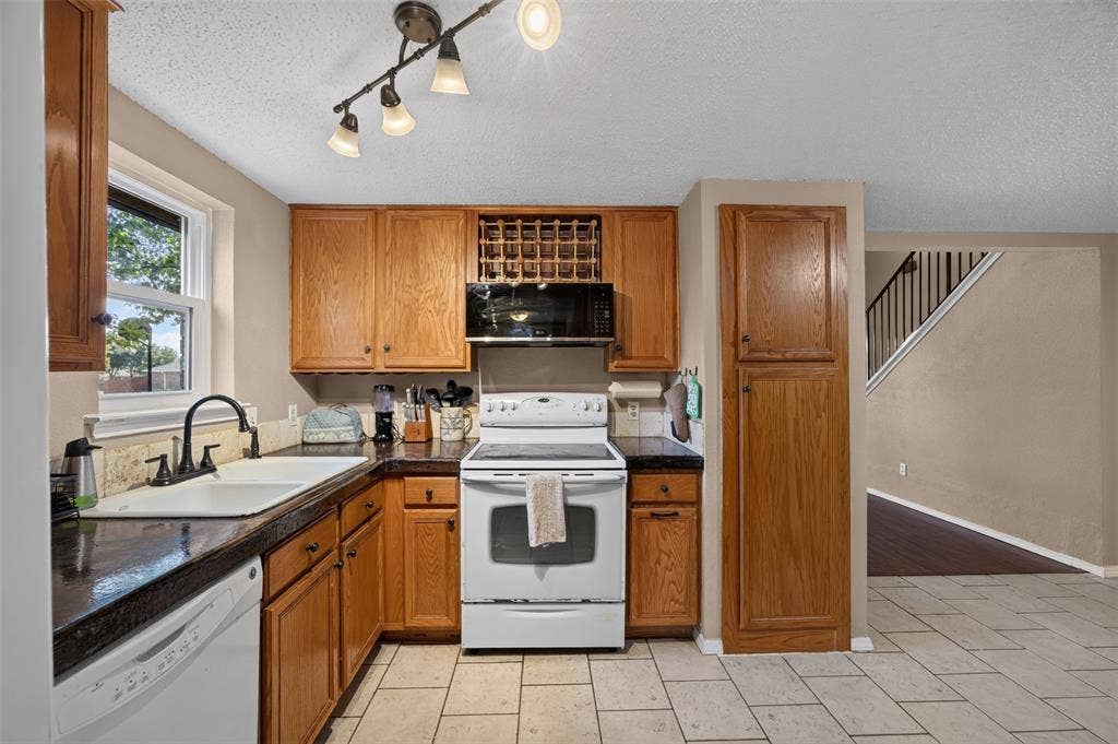 203 Briarglen Drive, Cedar Hill, TX 75104 Kitchen featuring wood cabinetry, dark countertops, a built-in microwave, white appliances, and a tile floor