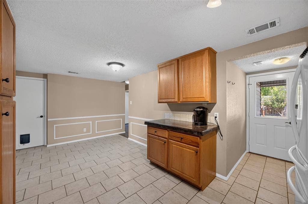 203 Briarglen Drive, Cedar Hill, TX 75104 Light wood-finish cabinetry with dark countertops, tiled flooring, and a paneled accent wall