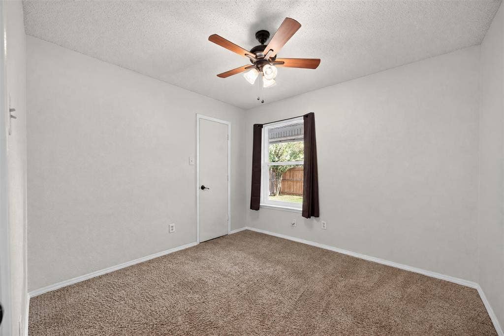 203 Briarglen Drive, Cedar Hill, TX 75104 Neutral wall paint with textured finish, ceiling fan with integrated lighting, window with exterior yard visibility, and brown carpet flooring