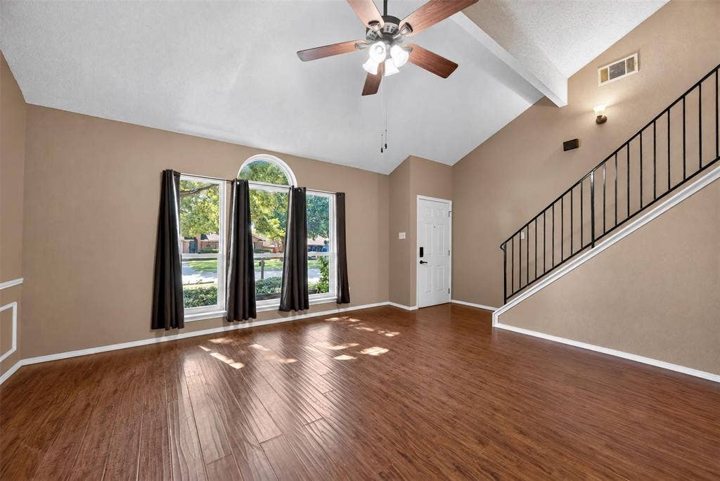 203 Briarglen Drive, Cedar Hill, TX 75104 Vaulted ceiling with a ceiling fan, wood-finish flooring, staircase with a black metal railing, prominent window featuring an arched transom, and a solid entry door
