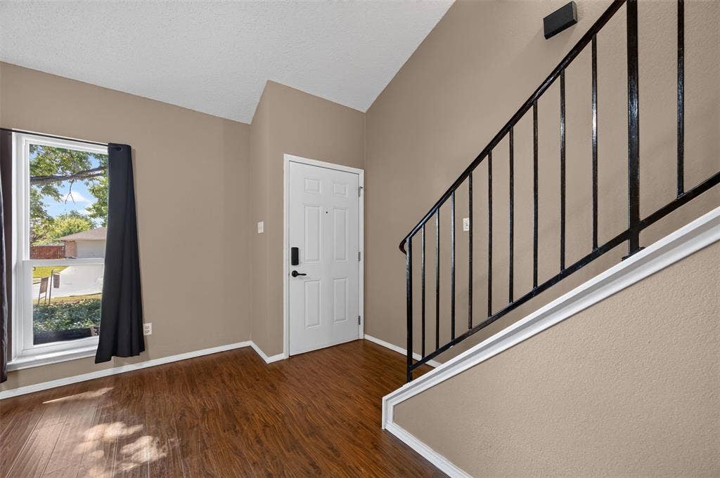203 Briarglen Drive, Cedar Hill, TX 75104 Vaulted ceiling, wood-finish flooring, white paneled entry door, black wrought iron railing, and a large window