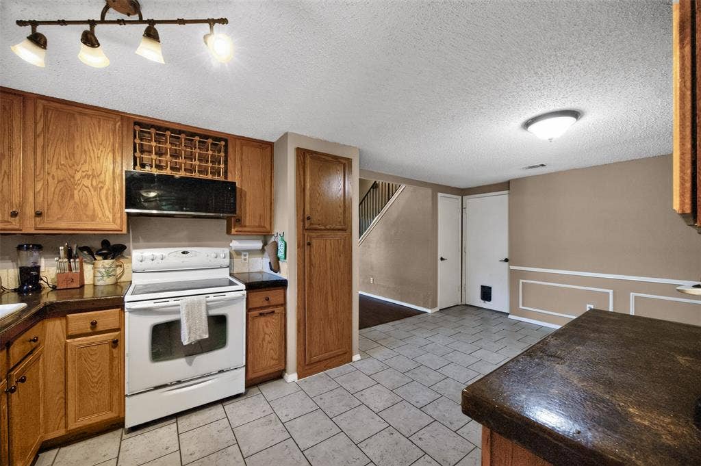 203 Briarglen Drive, Cedar Hill, TX 75104 Kitchen featuring wood cabinetry, built-in wine rack, tile flooring, and integrated white appliances