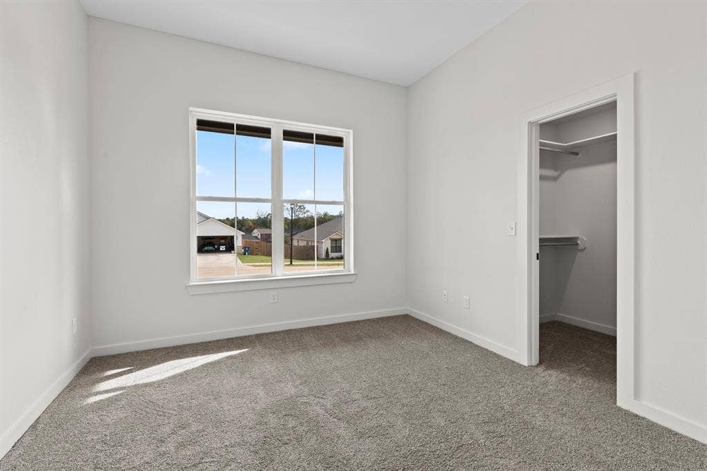 16514 Crossing Circle, Lindale, TX 75771 Carpeted room featuring a double window with exterior streetscape and a walk-in closet with built-in shelving
