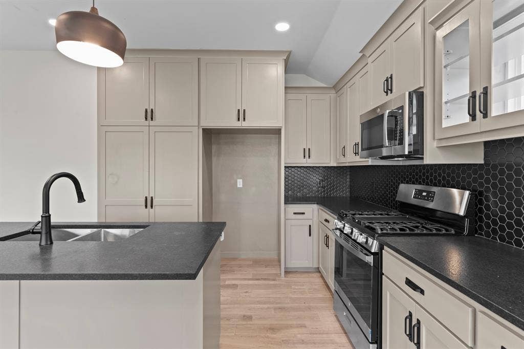 16514 Crossing Circle, Lindale, TX 75771 Contemporary kitchen featuring light-colored cabinetry, dark countertops, a black hexagonal tile backsplash, a stainless steel gas range, and a stainless steel built-in microwave