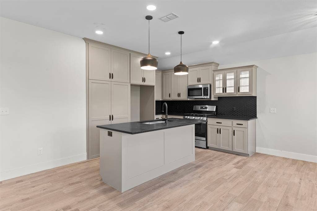 16514 Crossing Circle, Lindale, TX 75771 Kitchen featuring an island with a sink, recessed lighting, wood-finish flooring, full-height cabinetry, and stainless steel appliances