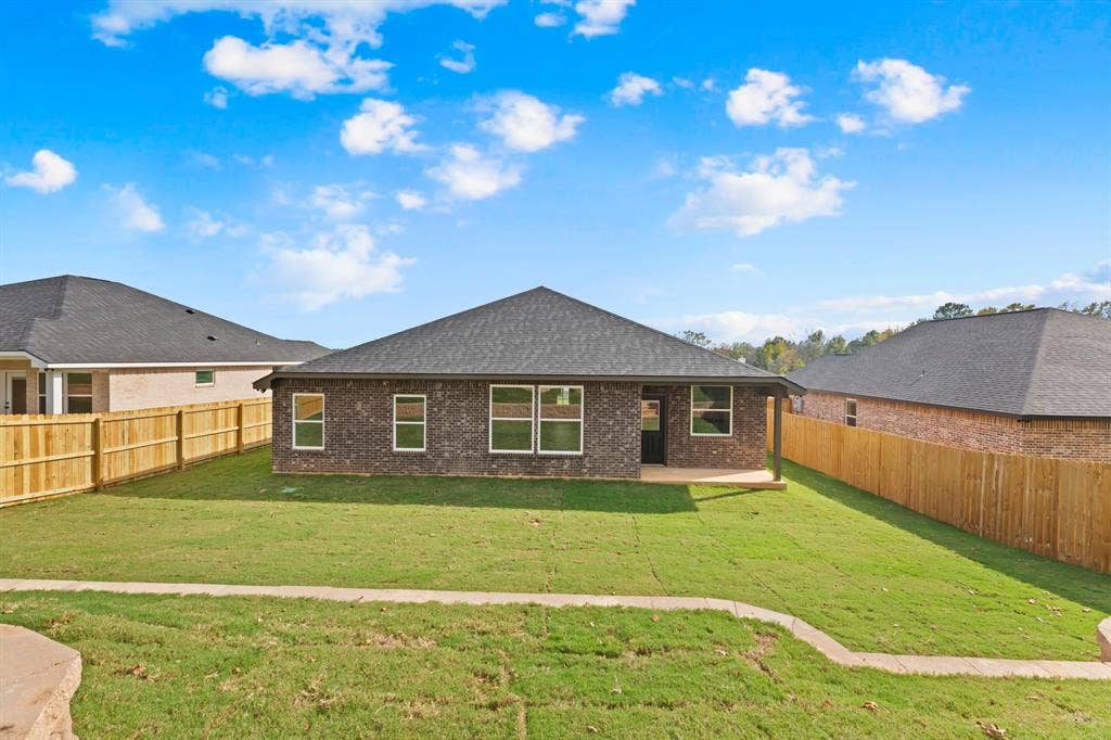 16514 Crossing Circle, Lindale, TX 75771 Expansive backyard featuring a manicured lawn, full privacy fencing, and a covered patio area