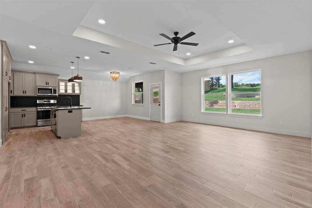 16514 Crossing Circle, Lindale, TX 75771 Open-concept living area with wood-finish flooring, a kitchen island, pendant lighting, and stainless steel appliances