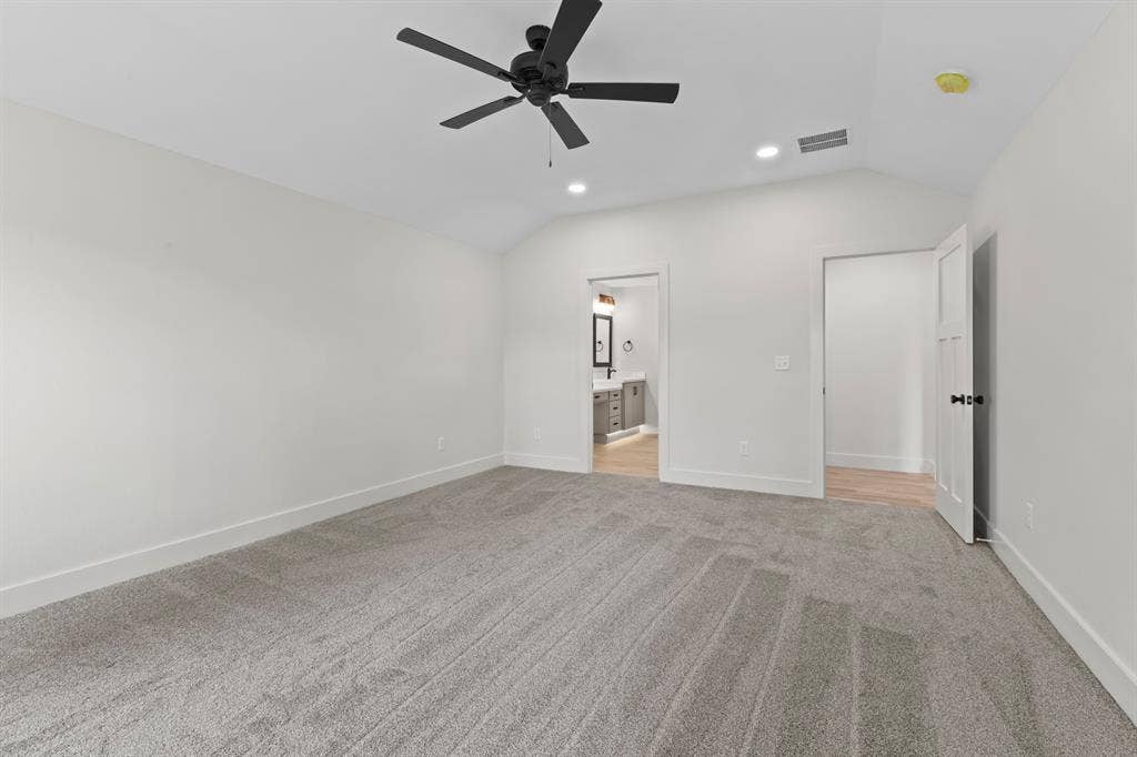 16514 Crossing Circle, Lindale, TX 75771 Vaulted ceiling with recessed lighting and a ceiling fan, carpeted flooring, and a door opening to a bathroom with a vanity and mirror