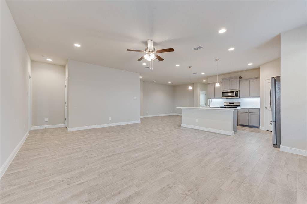 Unfurnished living room with ceiling fan and light hardwood / wood-style flooring