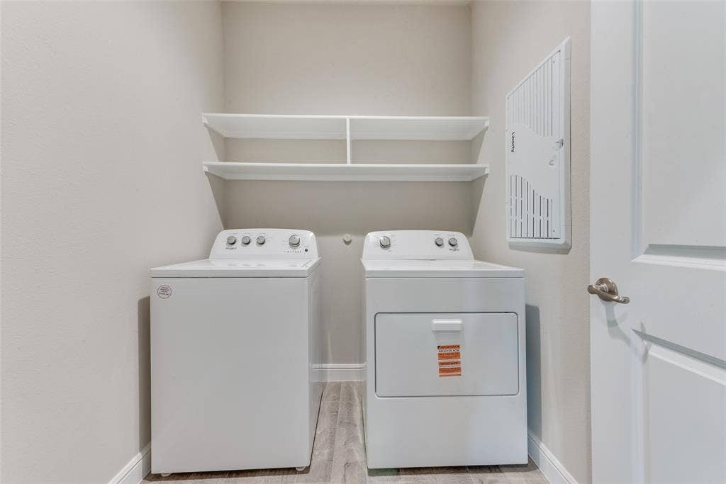 Clothes washing area featuring washing machine and clothes dryer and light hardwood / wood-style floors