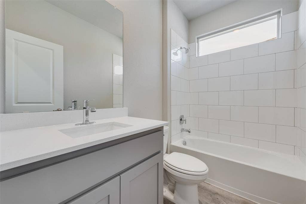 Full bathroom with vanity, toilet, and tiled shower / bath combo