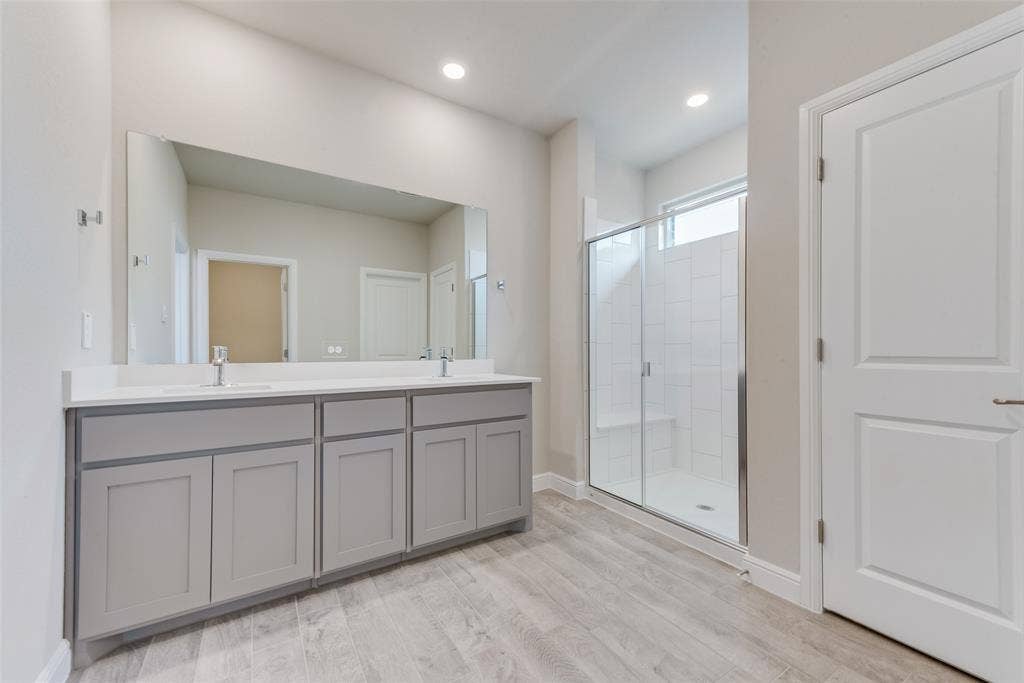 Bathroom with vanity, an enclosed shower, and wood-type flooring