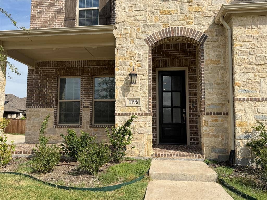 1196 Putnam Drive, Frisco, TX 75036 Brick and stone exterior with covered front porch, arched brick doorway, and a black paneled door