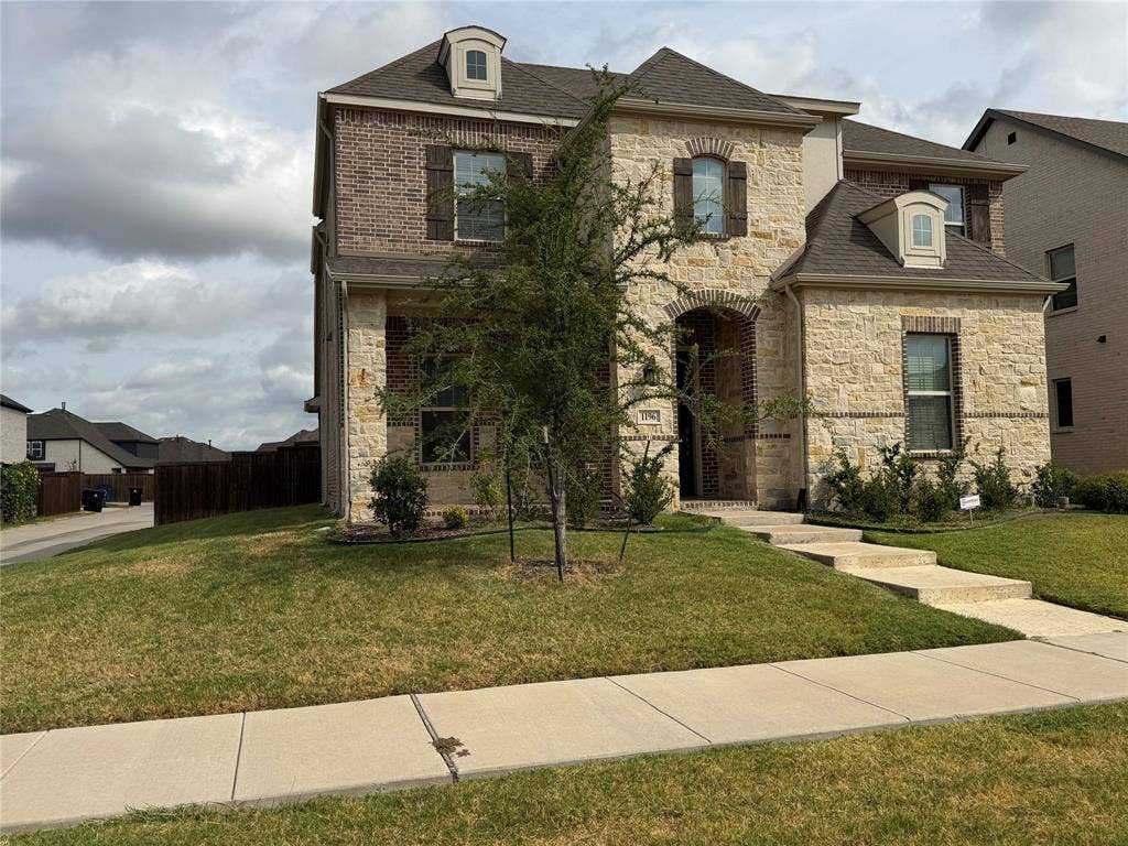 1196 Putnam Drive, Frisco, TX 75036 Two-story corner lot with a combination brick and stone facade, dormer windows, and dark wood shutters
