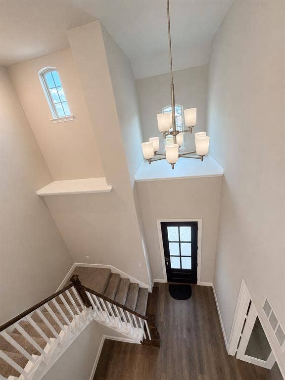 1196 Putnam Drive, Frisco, TX 75036 View of entry from upstairs of the two-story entry featuring high ceilings, wood-finish flooring, a contemporary chandelier, and a black paneled door with divided lites