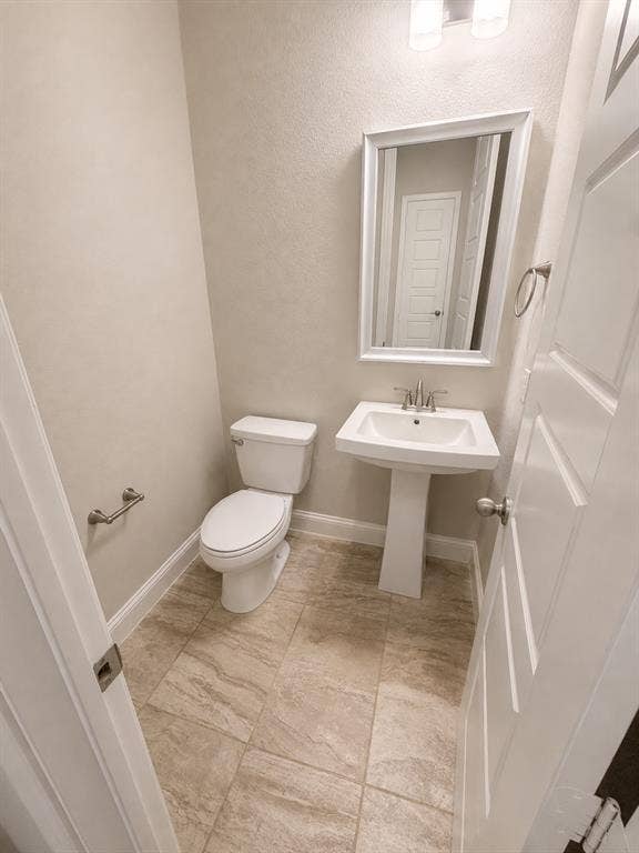 1196 Putnam Drive, Frisco, TX 75036 Guest bath downstairs with pedestal sink with a framed mirror and wall-mounted lighting