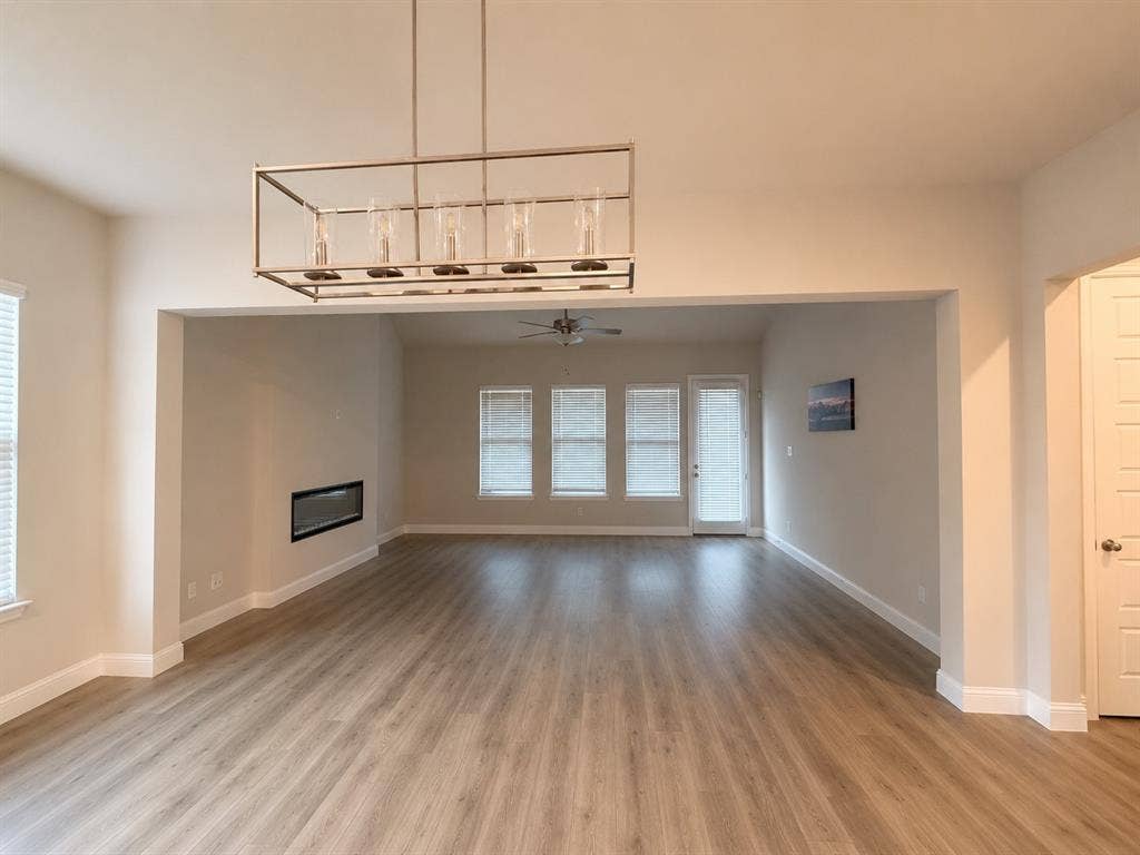 1196 Putnam Drive, Frisco, TX 75036 Texas sized family room with expansive interior, wood-finish flooring, a built-in linear fireplace, and an overhead chandelier