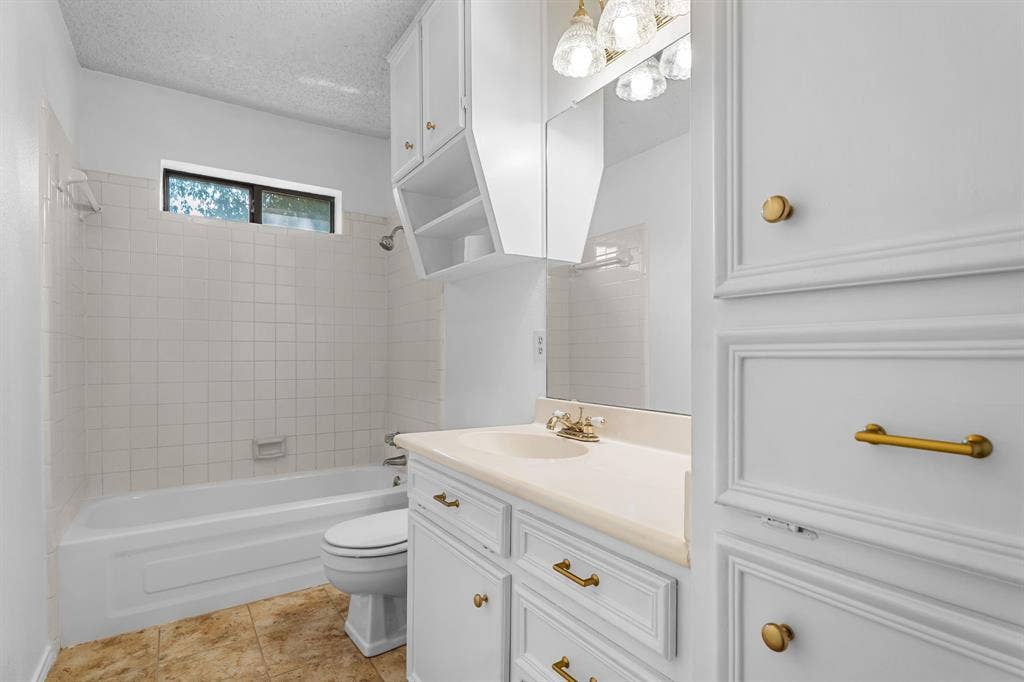 544 Jason Street, Robinson, TX 76706 White paneled cabinetry with brass hardware, light-colored countertop, integrated sink, and overhead vanity lighting