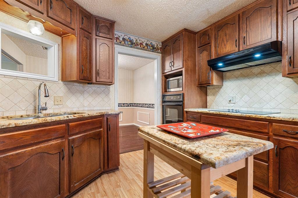544 Jason Street, Robinson, TX 76706 Kitchen featuring wood-finish cabinetry, granite countertops, tile backsplash, built-in microwave, and built-in oven