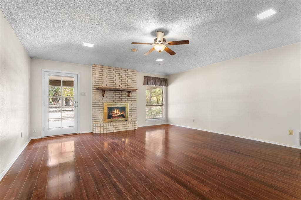 544 Jason Street, Robinson, TX 76706 Wood-finish flooring, brick fireplace with a wood mantle, ceiling fan, and a glass-paneled door