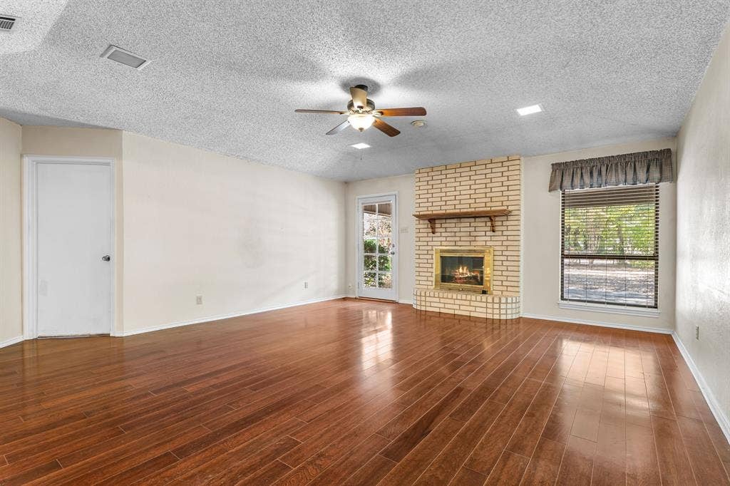 544 Jason Street, Robinson, TX 76706 Spacious room featuring wood-finish flooring, a brick fireplace with a mantel, a ceiling fan with integrated lighting, and recessed ceiling lights