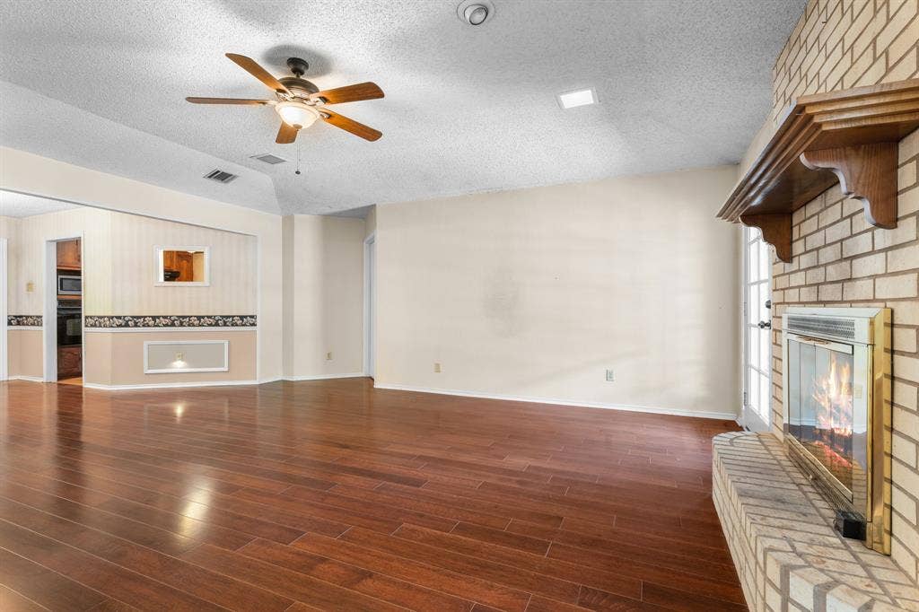 544 Jason Street, Robinson, TX 76706 Wood-finish flooring, brick fireplace with a wood mantle, vaulted ceiling, and a ceiling fan with integrated lighting