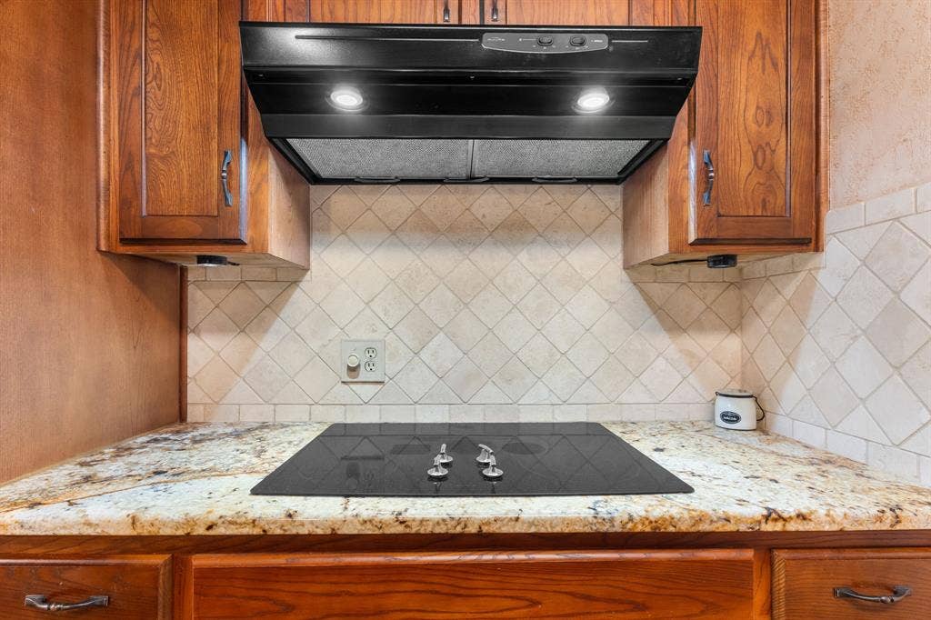 544 Jason Street, Robinson, TX 76706 Built-in cooktop with a range hood, natural wood cabinetry, light-toned stone countertops, and a diagonal tile backsplash