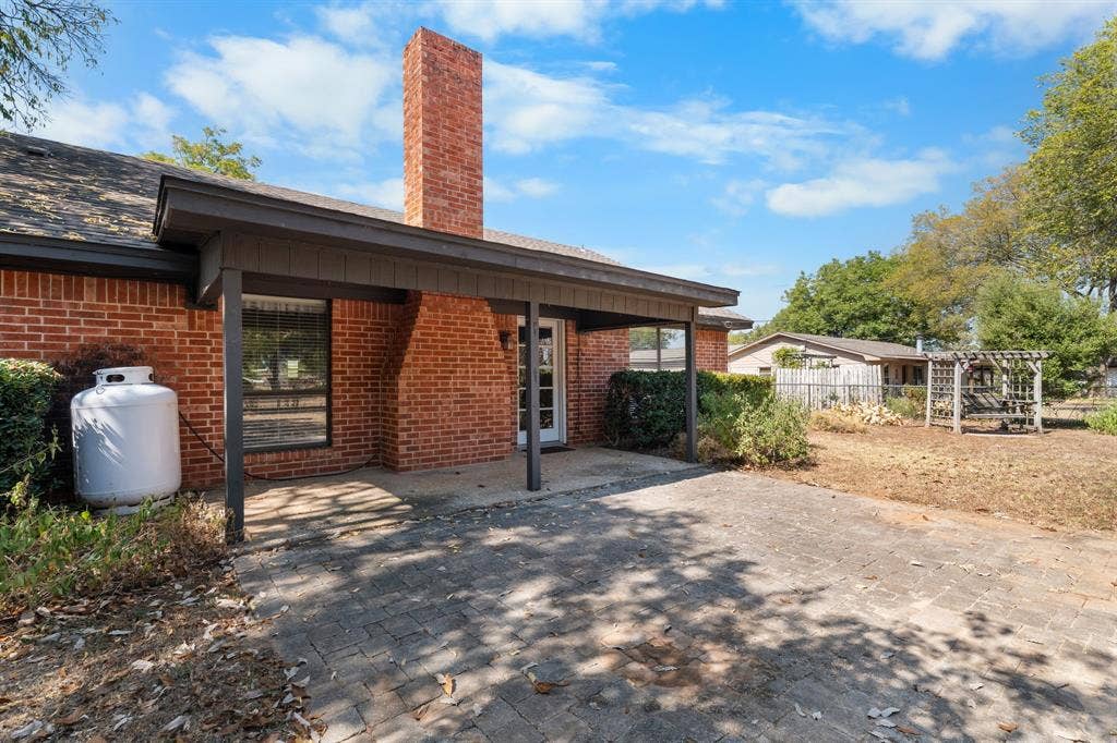 544 Jason Street, Robinson, TX 76706 Brick exterior with a covered patio, exposed brick chimney, and paved patio area