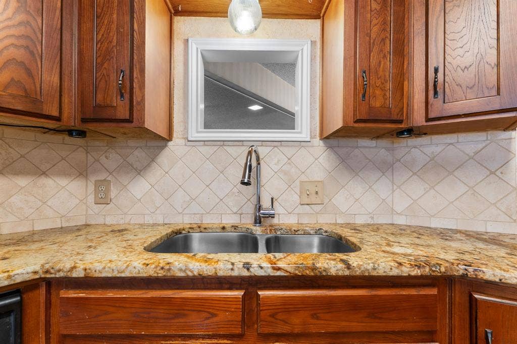 544 Jason Street, Robinson, TX 76706 Granite countertops, stainless steel double basin sink, chrome gooseneck faucet, diamond-patterned tile backsplash, and wood cabinetry