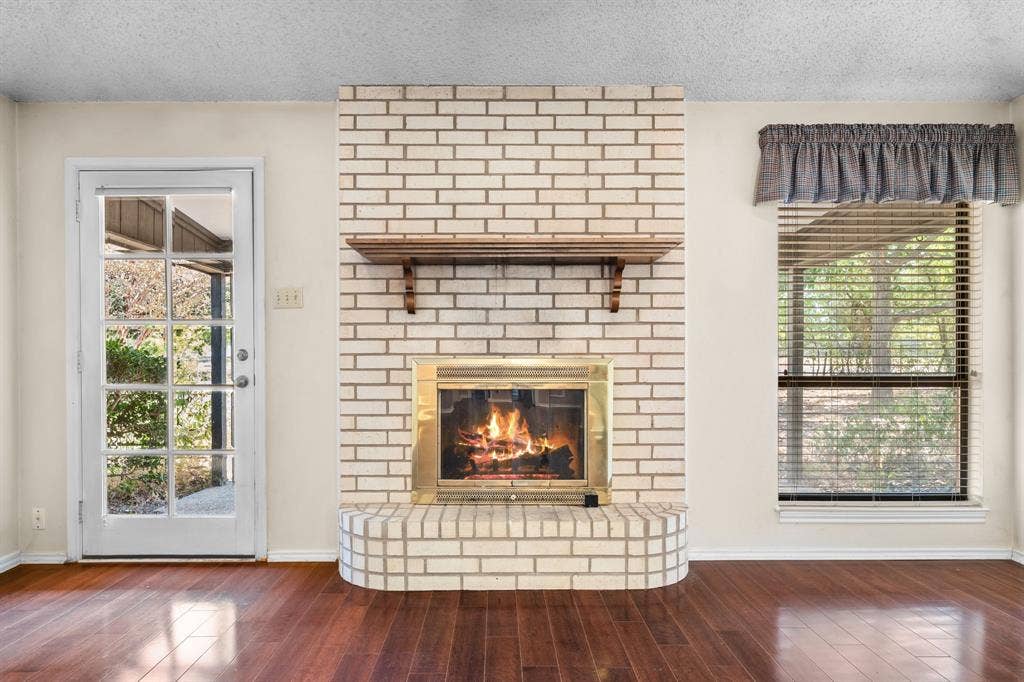 544 Jason Street, Robinson, TX 76706 Brick fireplace with a brass-trimmed firebox and wood mantel shelf, complemented by rich wood-finish flooring