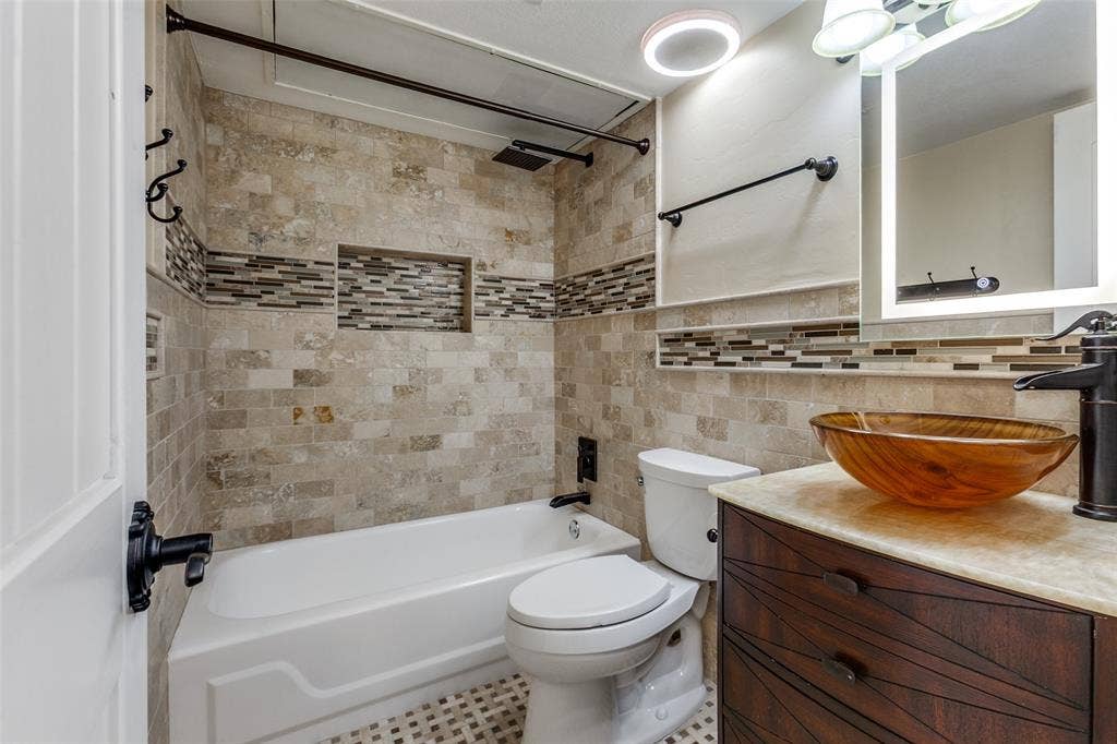 351 Valley Park Drive, Garland, TX 75043 351 Valley Park Dr. - 2nd floor bathroom featuring a beautifully updated bathtub, decorative mosaic tile accents, rustic wood vanity with vessel sink, and stylish fixtures.
