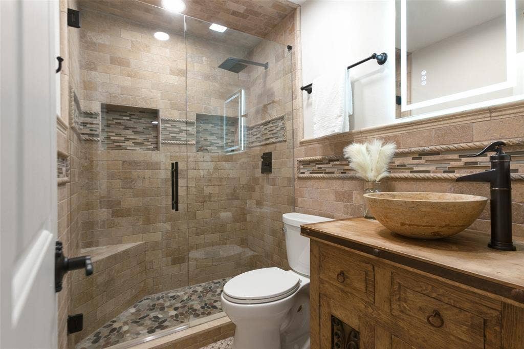 351 Valley Park Drive, Garland, TX 75043 351 Vally Park Dr. - First-floor bathroom featuring a beautifully updated walk-in shower with glass enclosure, decorative mosaic tile accents, pebble tile shower floor, rustic wood vanity with vessel sink, and stylish fixtures.