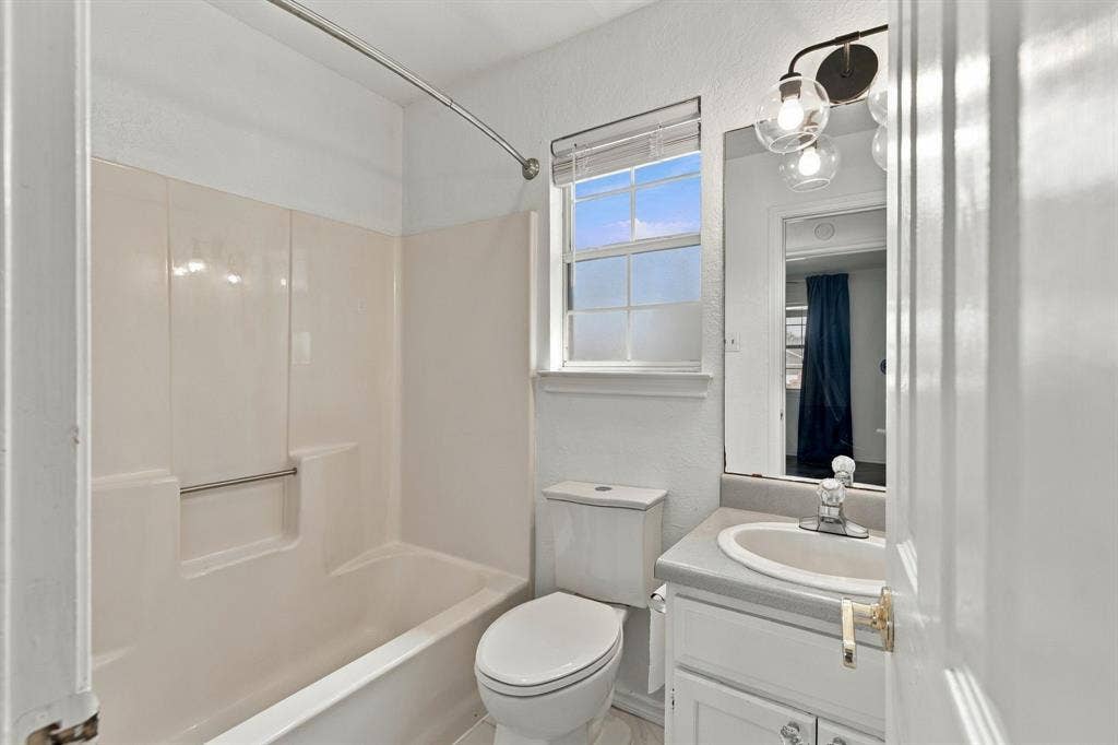 1015 Shelly Drive, Keene, TX 76031 White vanity with integrated sink, rectangular mirror, and a three-bulb sconce